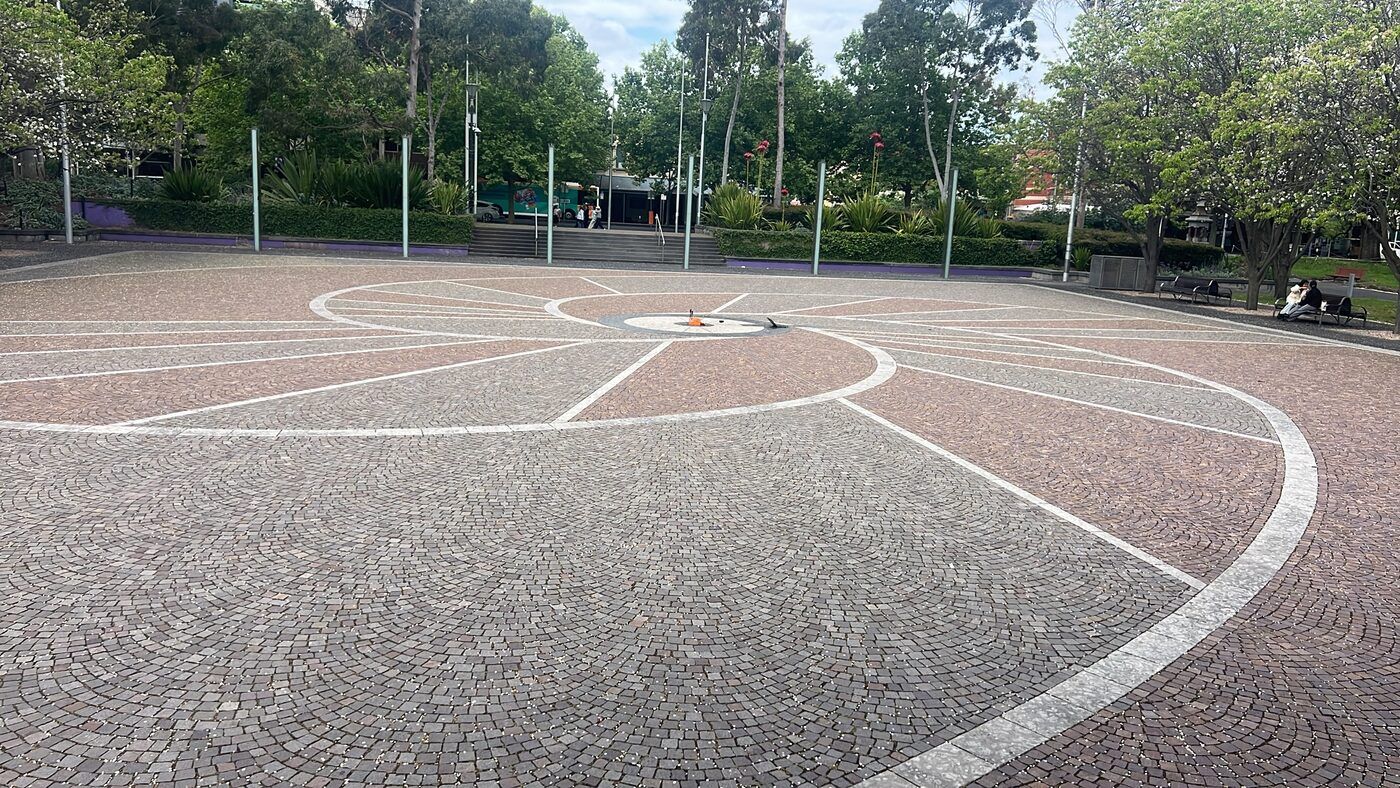 Argyle Square: a paved plaza with radiating painted lines and a central white disc, ringed by trees.